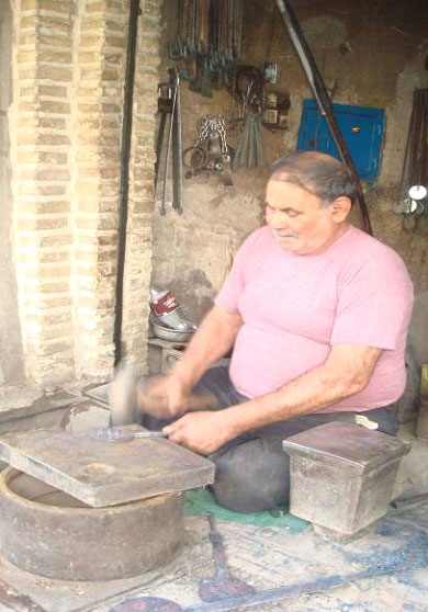 مردی در حال چکش زنی در بازار کهنه دزفول