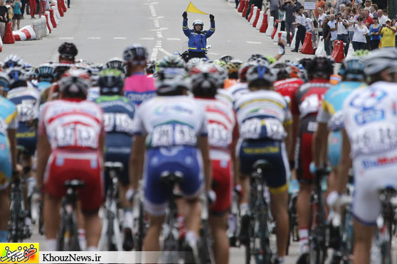 CAUTION: A French policeman waved a yellow flag to warn riders of an obstacle in the middle of the road during the start of the fifth stage of the Tour de France in Rouen, France, on Thursday. (Christophe Ena/Associated Press)